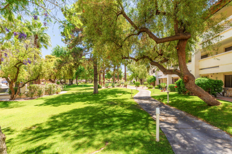Shaded walking path winding through lush gardens beside comfortable retirement living residences.