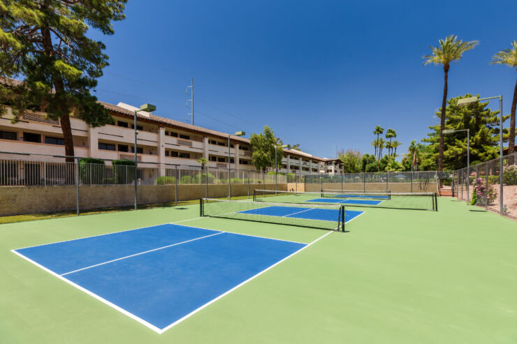 Well-maintained pickleball courts with surrounding greenery and comfortable retirement living spaces nearby.