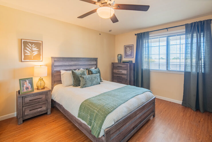 Sunlit bedroom with wooden furniture, green accents, and peaceful, inviting décor.