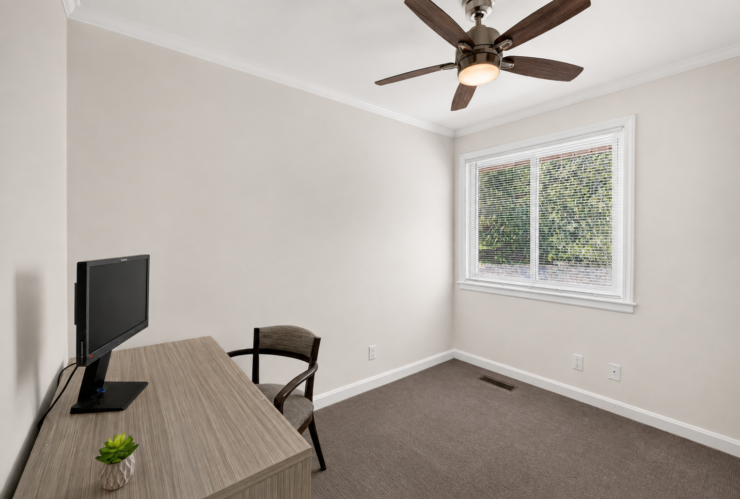Bright, peaceful room with desk, chair, TV, and window inviting natural light and calm.
