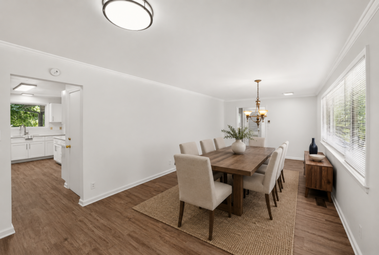 Dining area with wooden table and cushioned chairs, bright natural light and inviting decor.