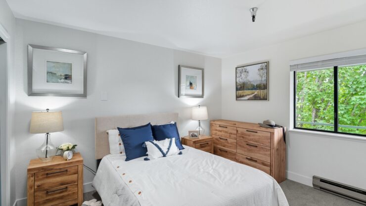 Bright bedroom with natural light, wooden furniture, and calming nature artwork for peaceful living.