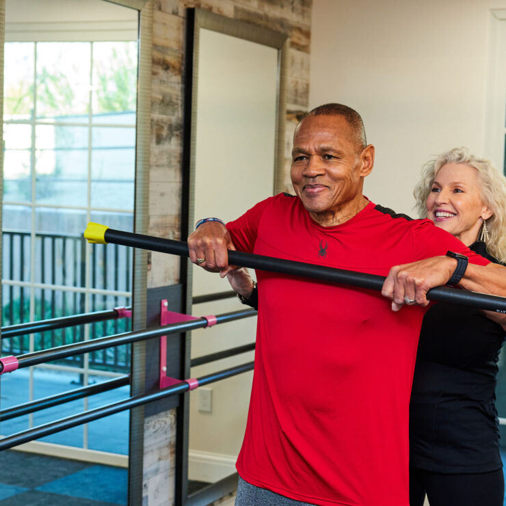 Senior residents engage in guided fitness exercises in a bright, welcoming activity room.