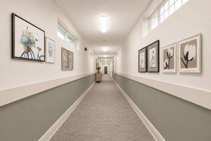 Well-lit hallway with soft colors and artwork, creating a welcoming and peaceful environment.