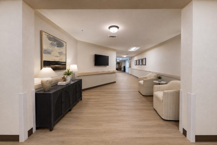 Well-lit hallway with comfortable seating, artwork, and welcoming décor in a community setting.