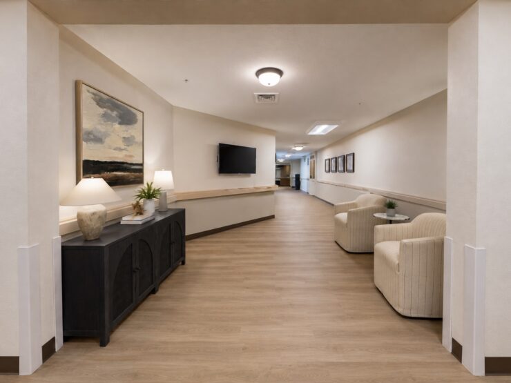 Well-lit hallway with comfortable seating, artwork, and welcoming décor in a community setting.