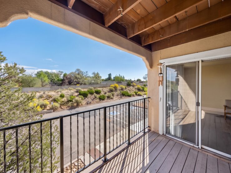Sunlit balcony overlooking landscaped gardens and serene natural surroundings.