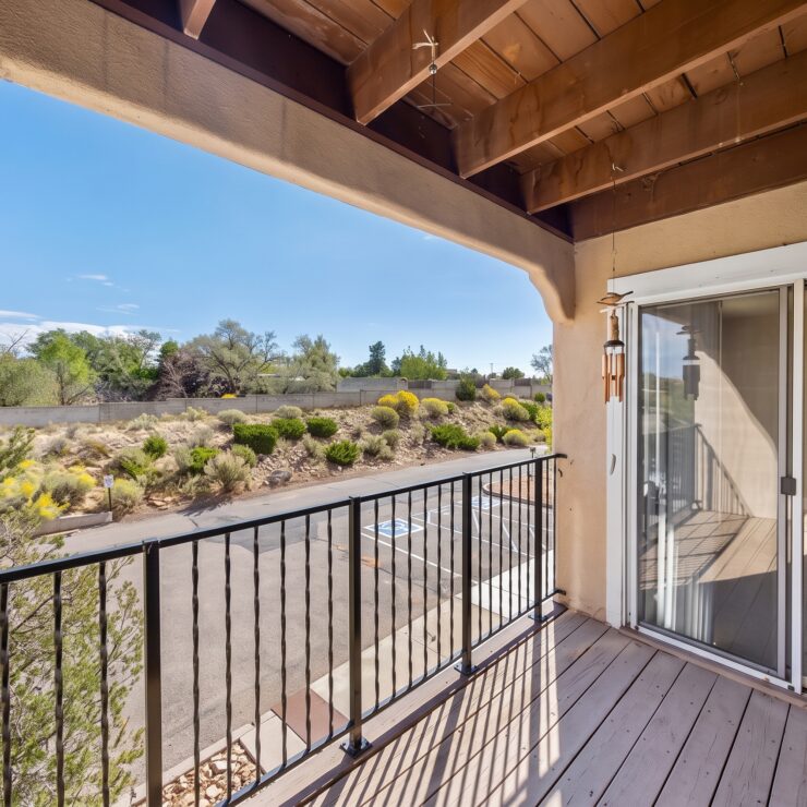 Sunlit balcony overlooking landscaped gardens and serene natural surroundings.