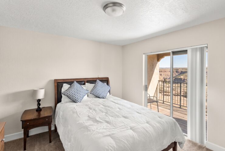 Well-lit bedroom with plush bedding, balcony access, and scenic desert views for peaceful living.
