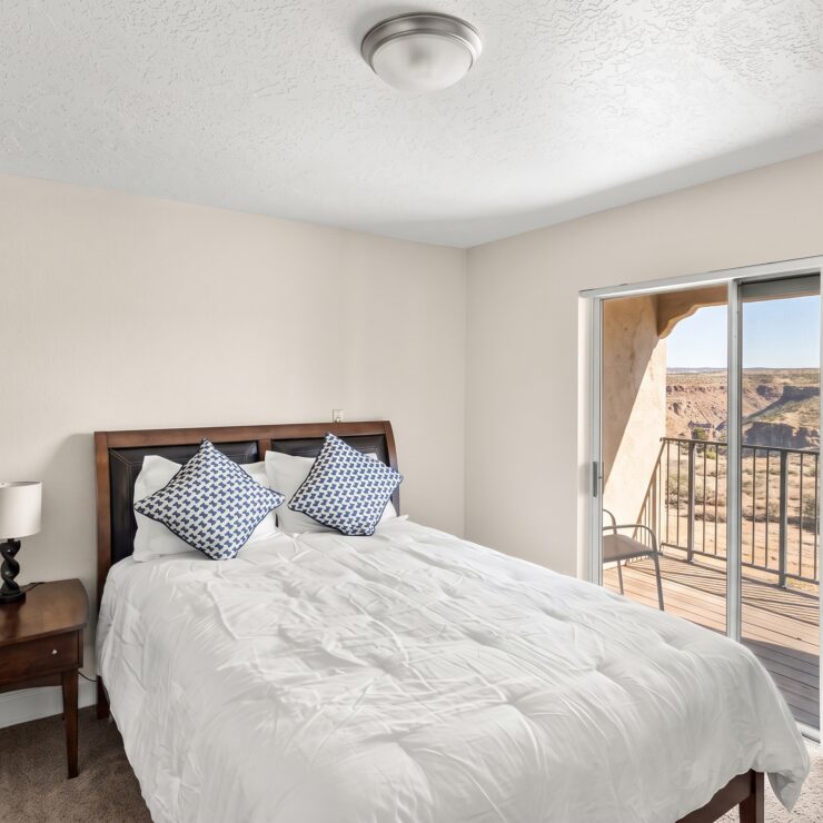 Well-lit bedroom with plush bedding, balcony access, and scenic desert views for peaceful living.