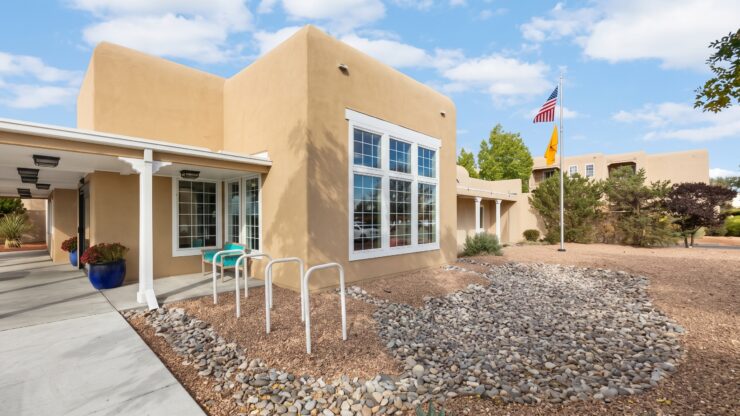 Sunlit Southwest-style building with seating and landscaped gardens promoting peaceful community living.