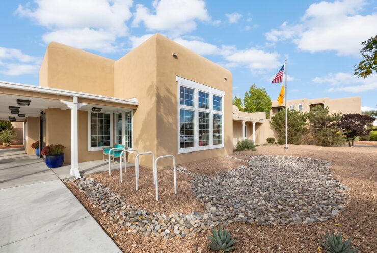 Sunlit Southwest-style building with seating and landscaped gardens promoting peaceful community living.