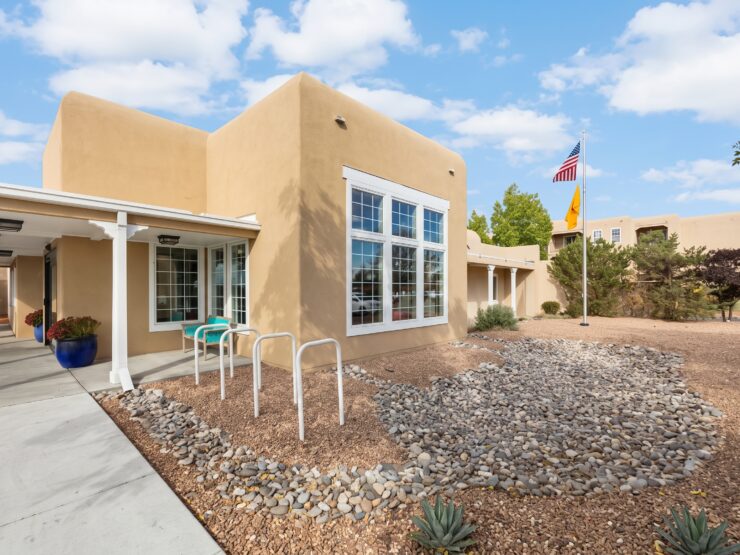 Sunlit Southwest-style building with seating and landscaped gardens promoting peaceful community living.