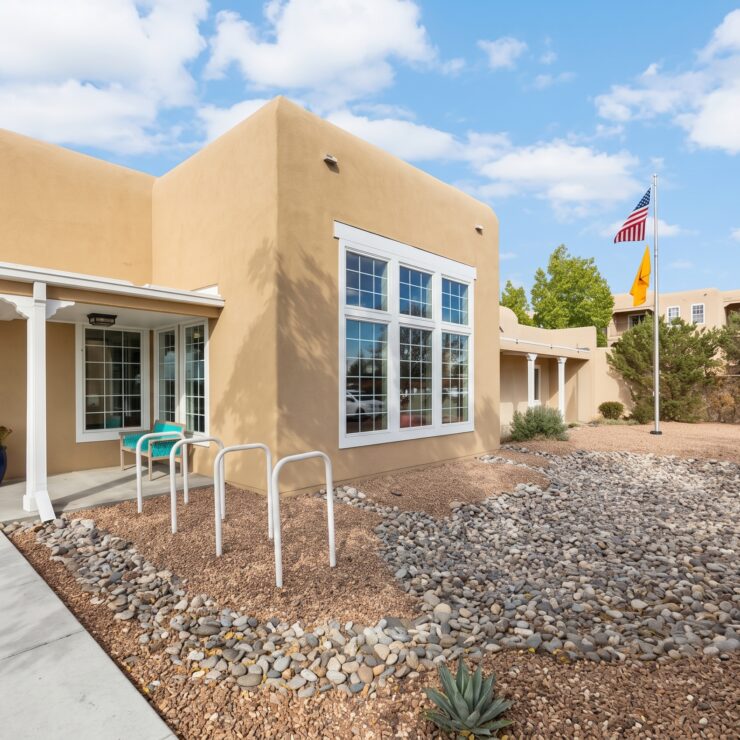 Sunlit Southwest-style building with seating and landscaped gardens promoting peaceful community living.