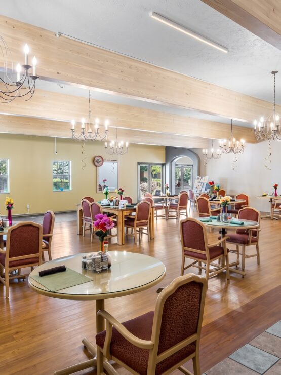 Spacious dining room with warm lighting, comfortable seating, and floral table accents fostering community.
