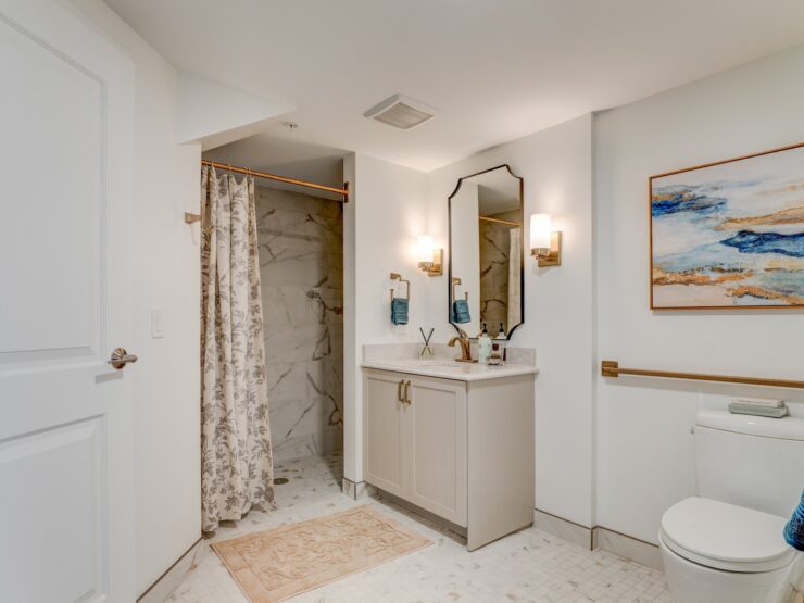 Bright bathroom with walk-in shower, elegant fixtures, and calming artwork for a welcoming feel.