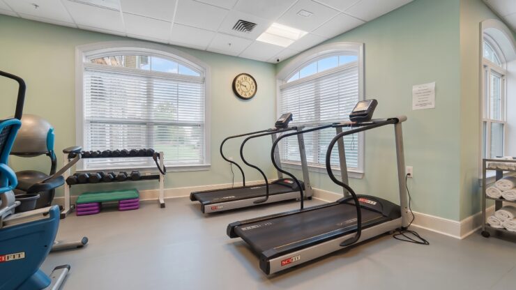 Well-lit fitness room with treadmills, weights, and exercise equipment promoting active living.