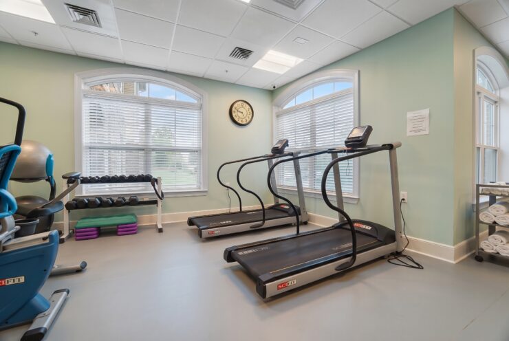 Well-lit fitness room with treadmills, weights, and exercise equipment promoting active living.