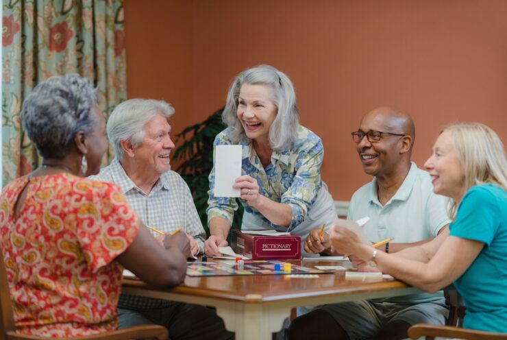 Seniors enjoying a lively board game in a warm, inviting community room with friendly smiles.