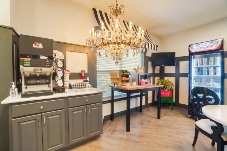 Bright and inviting snack area with coffee station, chandelier, and welcoming seating.