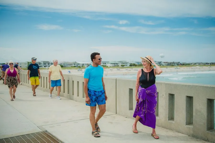 Seniors enjoying a sunny, friendly walk along the beachside promenade together.