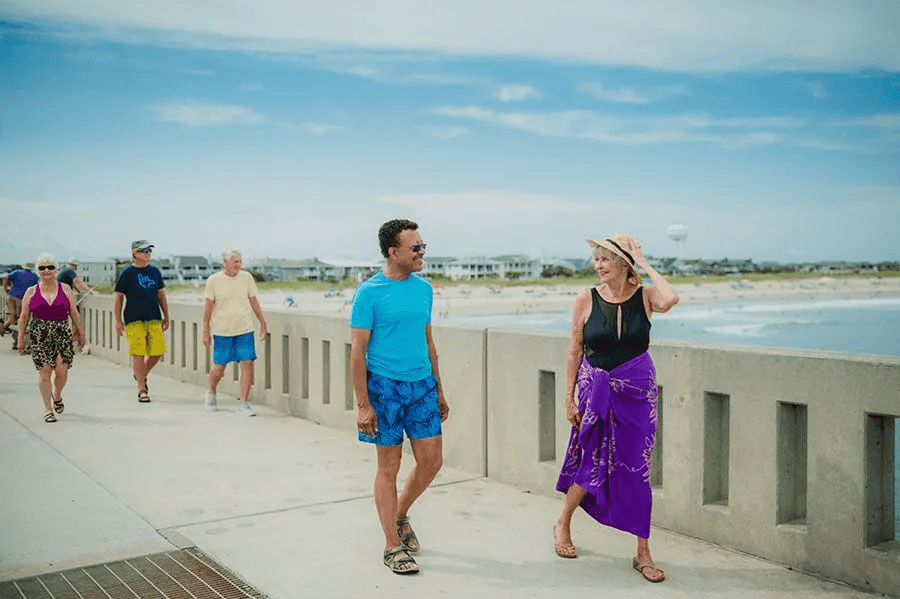Seniors enjoying a sunny, friendly walk along the beachside promenade together.
