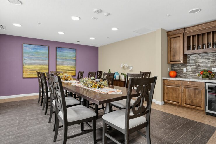 Bright dining area with a long table, comfortable chairs, and warm decorations.