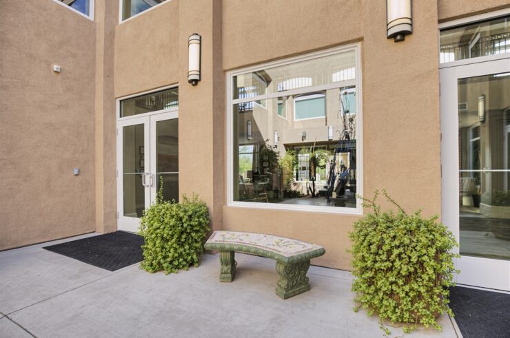 Outdoor seating area with greenery at the entrance of a welcoming retirement community.