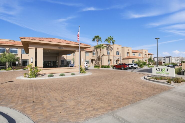 Sunny senior living community entrance with welcoming landscaping and accessible parking.