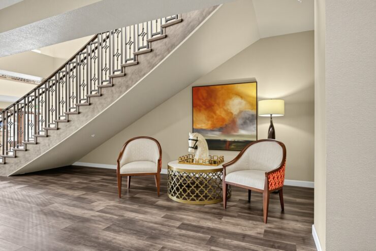 Welcoming seating area with comfortable chairs, artistic decor, and warm lighting under stairs.