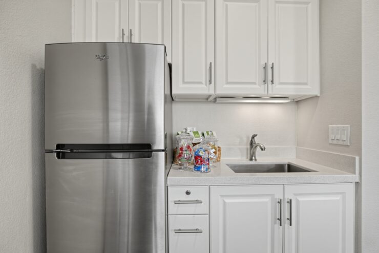 Modern kitchen area with white cabinets, stainless steel refrigerator, and a clean sink space.