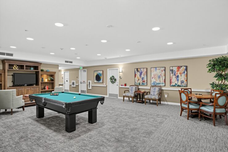Spacious community room with a pool table, seating areas, and warm, inviting decor.