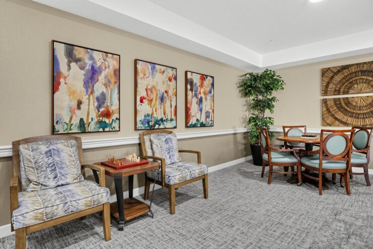 Comfortable seating area with artwork, a chess game, and a round table for social activities.