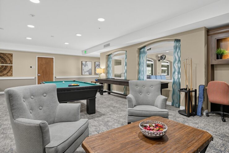 Relaxing lounge with comfortable chairs, pool table, and bright, inviting decor.