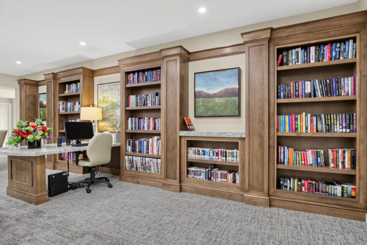 Well-lit library area with wooden bookshelves, a computer desk, and inviting decor.