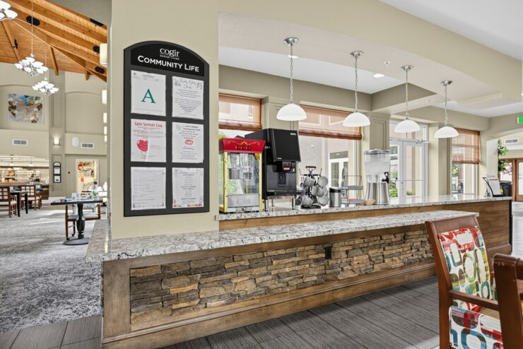 Bright and inviting community lounge with coffee station and comfortable seating in a senior living home.