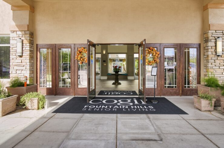 Entrance to a welcoming senior living community with autumn wreaths and inviting open doors.