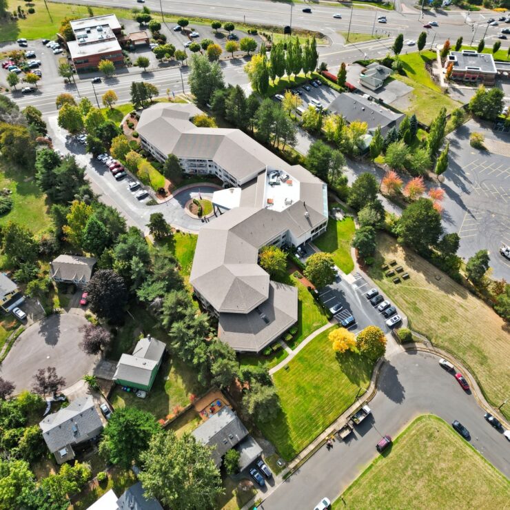 Retirement community nestled among trees with spacious grounds and nearby neighborhood roads.