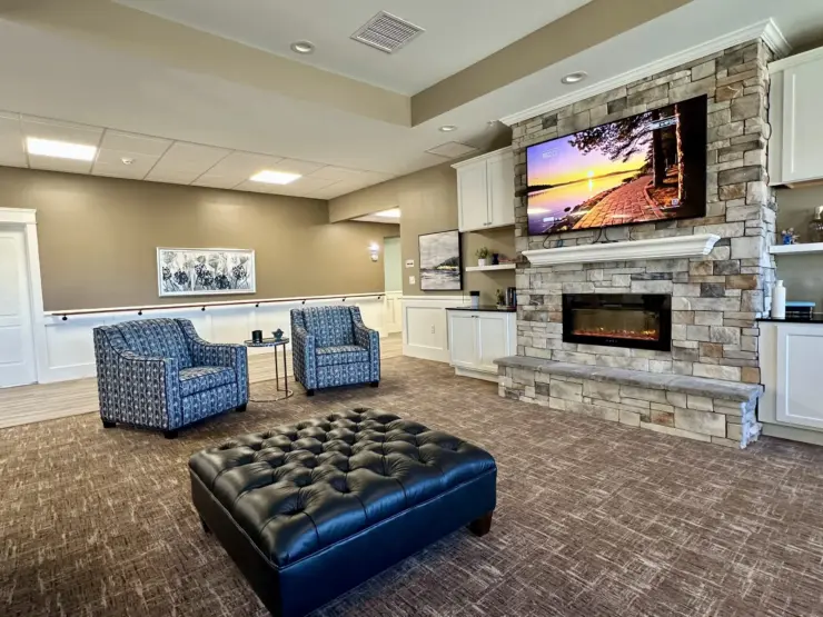 Inviting lounge area with comfortable seating, stone fireplace, and calming decor for community gatherings.