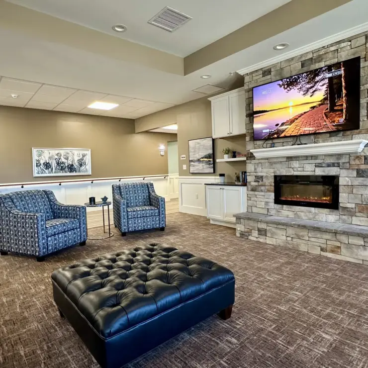 Inviting lounge area with comfortable seating, stone fireplace, and calming decor for community gatherings.