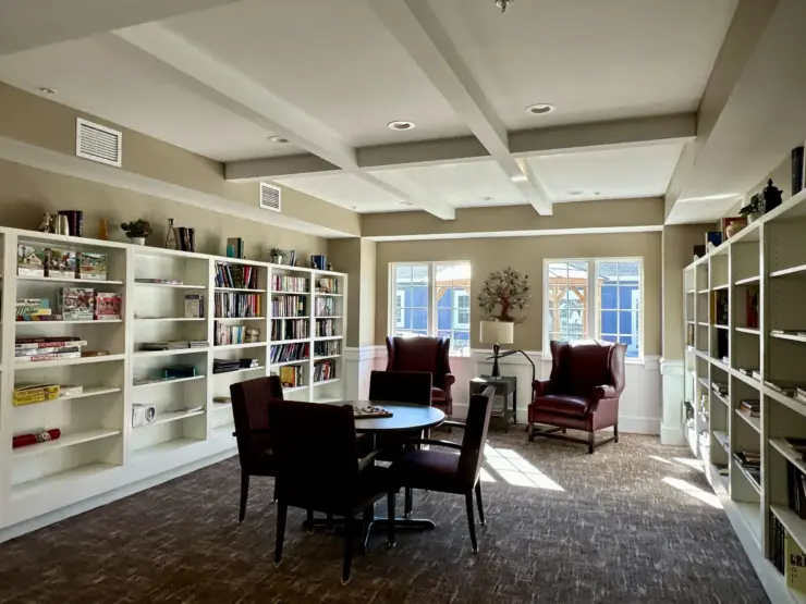 Bright and inviting community lounge with bookshelves, comfortable chairs, and natural light.