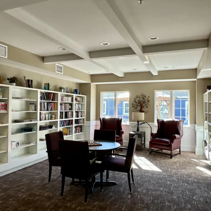 Bright and inviting community lounge with bookshelves, comfortable chairs, and natural light.