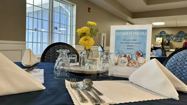 Dining table set with fresh flowers and a clear dinner menu in a bright, welcoming room.