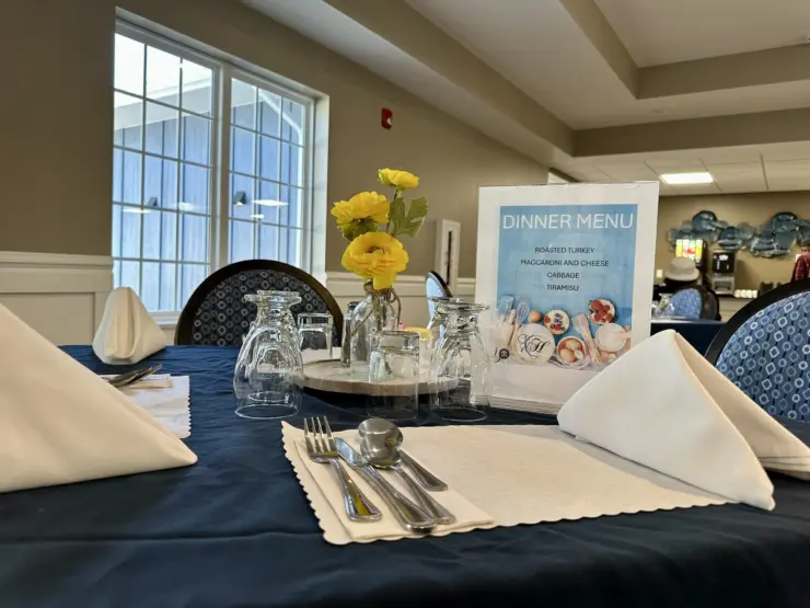 Dining table set with fresh flowers and a clear dinner menu in a bright, welcoming room.