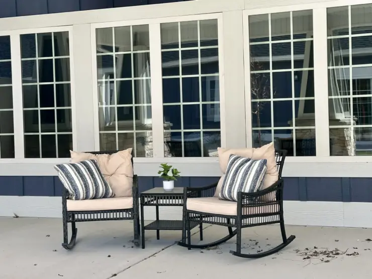 Outdoor seating area with cushioned rocking chairs and a small table creating a welcoming space.