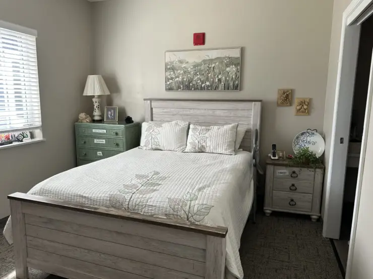 Well-lit bedroom with comfortable bed, personal touches, and calming decor for a peaceful stay.