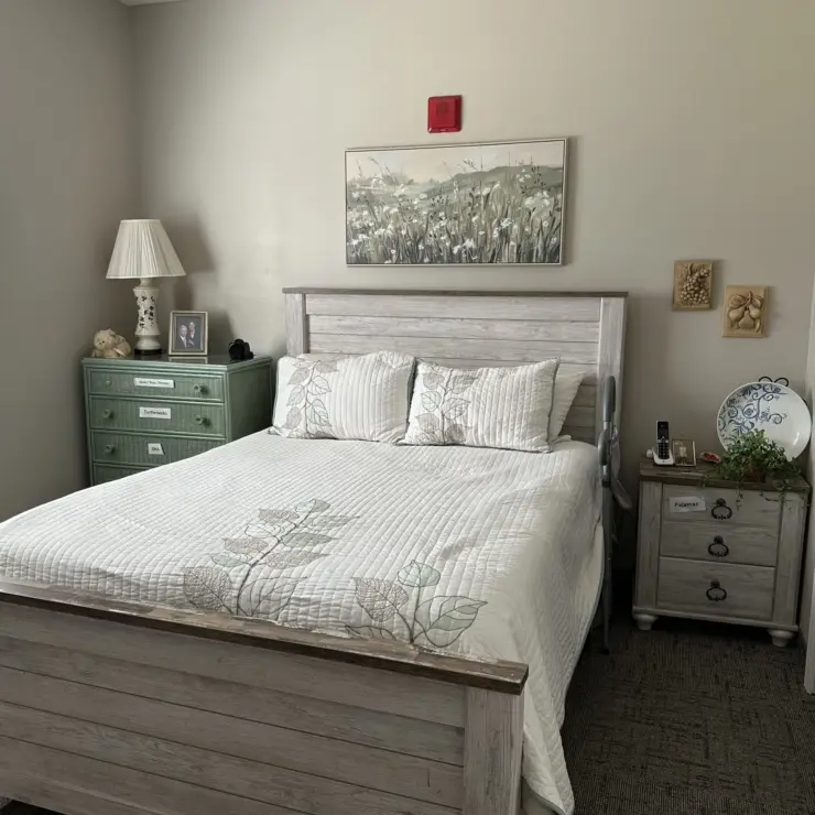 Well-lit bedroom with comfortable bed, personal touches, and calming decor for a peaceful stay.