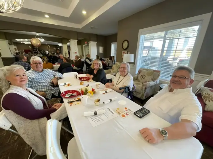Seniors enjoying a lively community meal in a bright, welcoming dining room setting.
