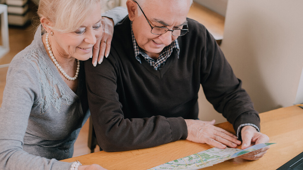 Older man and woman sitting looking at a map