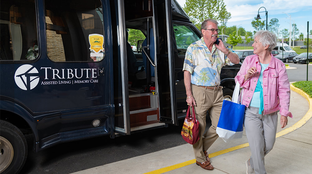 Mature couple steps off bus after day spent shopping